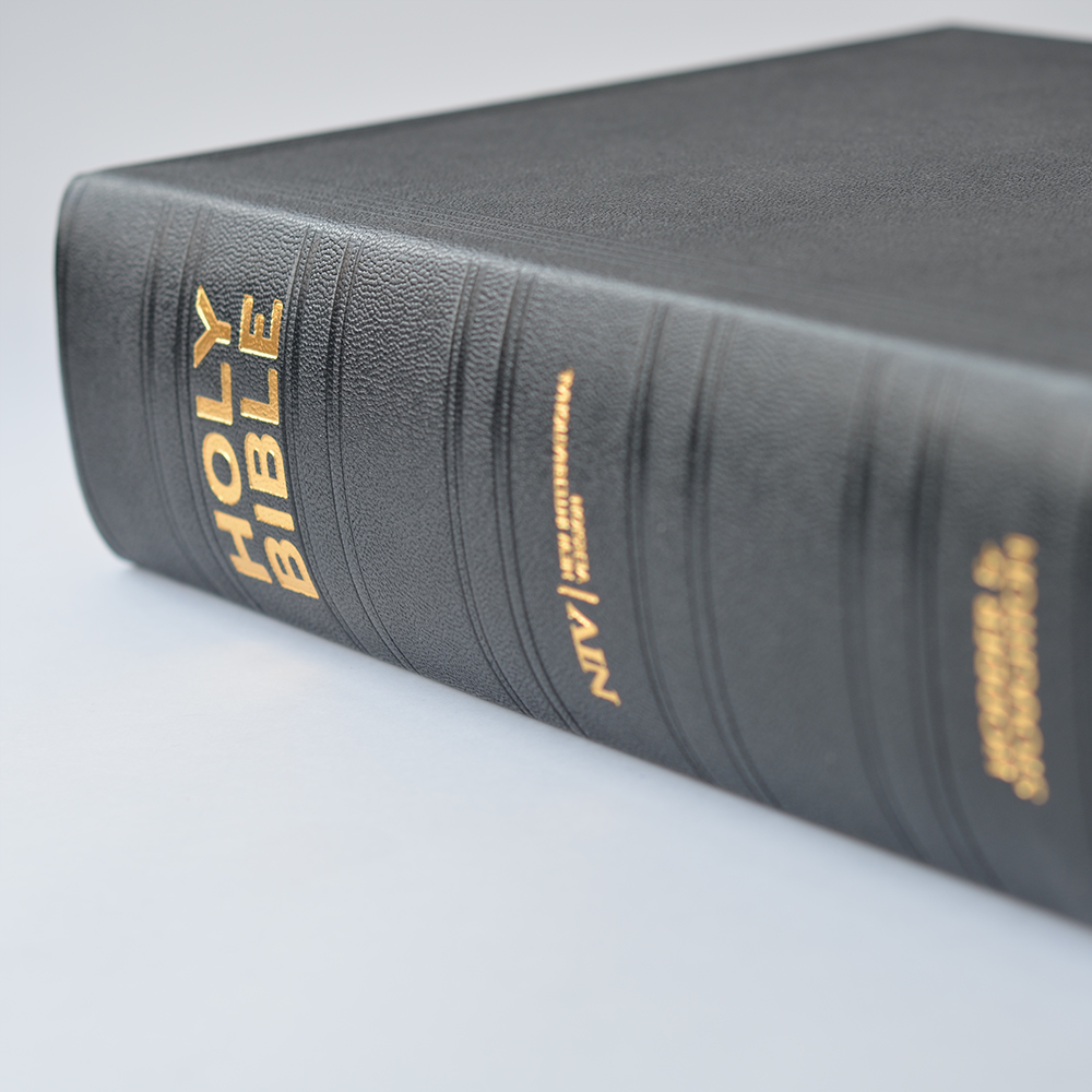 The lectern edition lying flat, displaying gold foil lettering on spine and black Moroccan leather binding